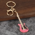 Gros plan sur le porte-clés mini guitare électrique rose orné de strass blancs - Or KC Avec Rose