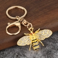 Goldener Bienen Schlüsselanhänger mit Kristallen und Emaille auf steiner Steinoberfläche - Gold