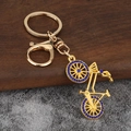 Detailed view of a gold bicycle keychain featuring blue rhinestone studded wheels - Gold Plated Blue Rhinestone