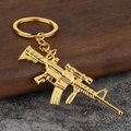 Golden PUBG M4 rifle keychain pendant made of metal alloy on a dark textured background - Gold