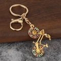 Detailed view of a golden bicycle keychain with colorful rhinestones on a wooden surface - Gold Plated Multi-color Rhinestone