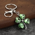 Macro view of green crystal clover keychain with silver metal clasp on wooden stand - Silver with Pale Green