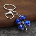 Detail view of a sparkling four-leaf clover keychain with deep blue heart crystals - Silver & Blue