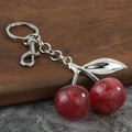 Glittery red resin cherry keychain with silver metal leaves on a walnut display base - Silver Light Red
