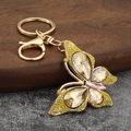 Sparkling crystal butterfly keychain with gold zinc alloy lobster clasp on wooden surface - Yellow