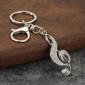 Vista detallada de un llavero plateado con forma de clave de sol y brillantes diamantes de imitación - Plata + Diamantes de Imitación Blancos