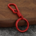 Detalle de un mosquetón rojo de aleación de zinc sobre una superficie de madera rústica - Rojo