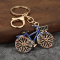Golden luxury bicycle keychain with deep blue enamel and vibrant rainbow rhinestones - Gold + Blue