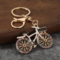 Detail shot of golden bicycle keychain with rhinestones and white enamel finish - Gold+White