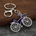 Macro view of a purple enamel bicycle keychain with sparkling rhinestones and metal lobster clasp - Silver Base Purple Frame