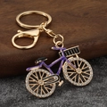 Detail of creative bicycle keychain with purple enamel finish and rhinestone encrusted wheels - Gold Base Purple Frame