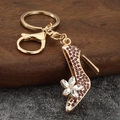 Detailed view of a gold high heel keychain with purple rhinestones and crystal flower detail - Purple
