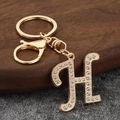 Close-up of golden letter H keychain charm with sparkling rhinestones and lobster clasp - Letter H