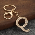 Close-up of gold letter Q keychain with sparkling rhinestones and lobster clasp hooks - Letter Q