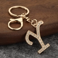 Macro detail of a gold letter Y keychain with sparkling white rhinestones on dark wood - Letter Y