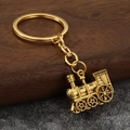 Detailed close-up of a vintage golden steam locomotive keychain on a textured surface - Antique Gold (Blackened Gold)