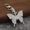 Détail d'un porte-clés papillon argenté serti de cristaux sur support en bois - Base Argentée Strass Blanc