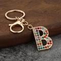 Dettaglio portachiavi lettera B con strass colorati su base in metallo dorato - Lettera B