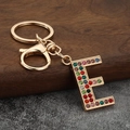 Macro detail of golden letter E keychain encrusted with colorful vibrant rhinestones - Letter E