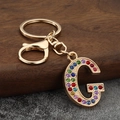 Macro view of colorful rhinestone letter G keychain with gold lobster clasp and ring - Letter G