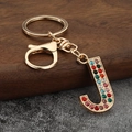 Close-up of letter J keychain featuring colorful rhinestones on a gold metal frame - Letter J