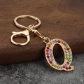 Macro detail of golden letter Q keychain charm with vibrant multi-colored crystal rhinestones - Letter Q