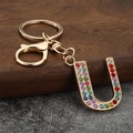 Close-up of letter U keychain with colorful rhinestones on a rustic wooden background - Letter U