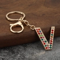 Macro detail of golden letter V keychain featuring colorful rhinestones and lobster clasp - Letter V