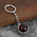 Close-up of luminous zodiac keychain featuring a red nebula glass ball with silver metal ring - Cancer