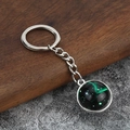 Detailed close-up of luminous green constellation glass cabochon silver keychain - Sagittarius