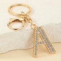 Detalle de un llavero dorado con la letra A y brillantes diamantes de imitación en piedra - Letra A