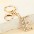 Detailed view of golden letter E keychain with sparkling crystals on stone background - Letter E