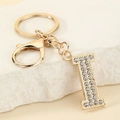 Detail of gold letter I keychain with sparkling crystals and lobster clasp on stone - Letter I