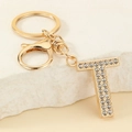 Macro detail of golden letter T keychain with sparkling white rhinestones inlay - Letter T