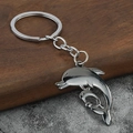 Makroaufnahme von Delphin-Schlüsselanhänger in Silber mit Mutter-Kind-Motiv auf Holz - Gunmetal