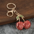 Portachiavi con ciliegie rosse scintillanti in metallo dorato e strass verdi - Rosso