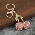 Portachiavi a ciliegia dorato con strass rosa e verdi su sfondo scuro decorativo - Rosa