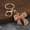 Portachiavi a fiocco con strass rosa brillanti, moschettone in metallo dorato e trama floreale - Rosa