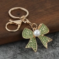 Elegante portachiavi a fiocco dorato con cristalli verde smeraldo e perla bianca - verde chiaro