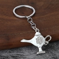 Detailed macro view of an Aladdin lamp keychain with white enamel and sparkling rhinestones - Silver & White