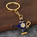 Macro shot of gold Aladdin magic lamp keychain with blue enamel and crystal inlay - Gold + Blue