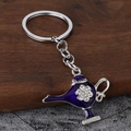 Macro shot of purple Aladdin lamp keychain with white rhinestones on dark wooden surface - Silver + Purple