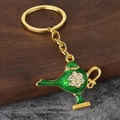 Close-up of golden Aladdin lamp keychain with green enamel and sparkling rhinestones - Gold + Green