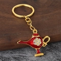 Close-up of golden Aladdin lamp keychain with red enamel and inlaid white crystals - Gold+Red