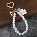 Llavero de perlas con flor blanca, colgantes de arcoíris y cierre de corazón sobre fondo piedra - Arcoíris + Flor Azul + Perla
