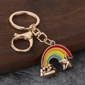 Porte-clés arc-en-ciel avec étoile dorée et fermoir mousqueton sur fond de pierre chic - Doré