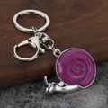 Detalle de llavero de caracol plateado con esmalte púrpura sobre madera y piedra - Plata-Púrpura