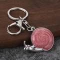 Llavero de caracol con purpurina rosa y baño de plata sobre fondo de madera y piedra - Plata-Rosa