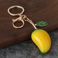 Dettaglio di un portachiavi a forma di mango in resina con anello dorato su legno - Mango Giallo + Ferramenta Oro (KC Oro)
