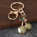 Glinsterende kersensleutelhanger met groene strassteentjes en gouden metalen ring - Groen